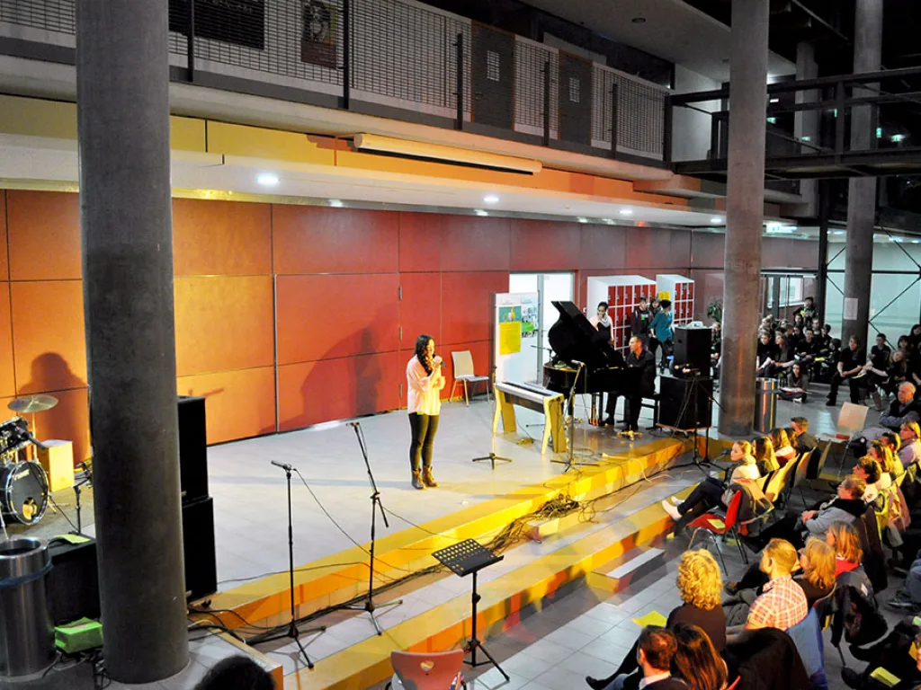 Person singt allein an einem Mikrofon im Foyer.